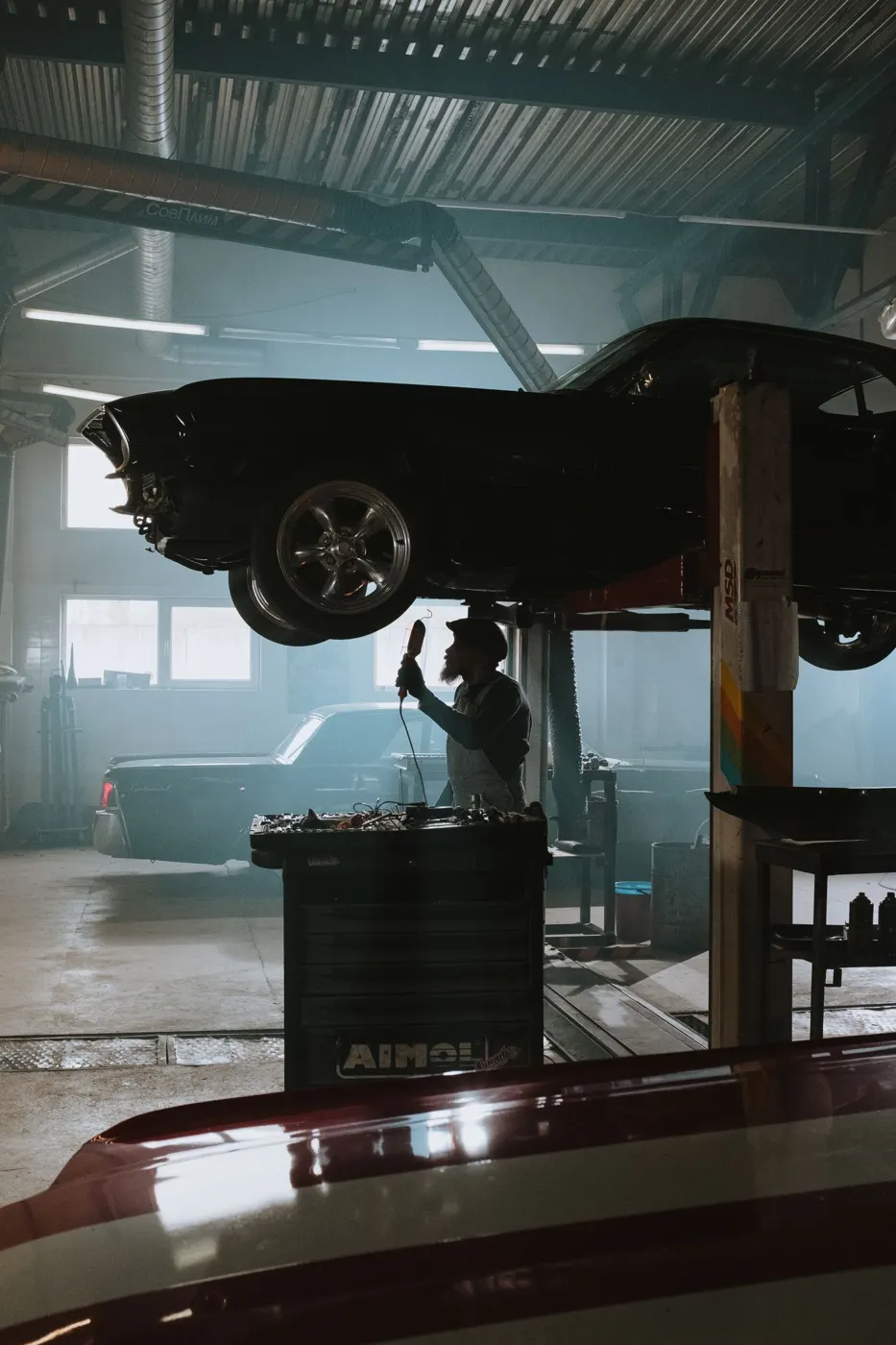 Car raised on a lift in the shop bay